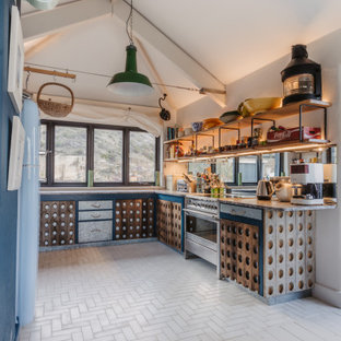 Medium sized coastal u-shaped kitchen in Cornwall with marble worktops, cement flooring, no island, white floors, black worktops, medium wood cabinets and a vaulted ceiling.