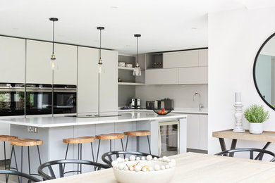 This is an example of a large contemporary l-shaped open plan kitchen in Hertfordshire with ceramic flooring, an island, white floors and white worktops.