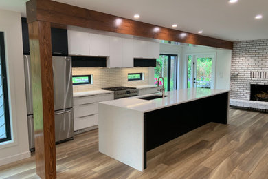 Inspiration for a large scandinavian galley vinyl floor, beige floor and exposed beam eat-in kitchen remodel in Edmonton with an undermount sink, flat-panel cabinets, white cabinets, quartz countertops, white backsplash, ceramic backsplash, stainless steel appliances, an island and white countertops