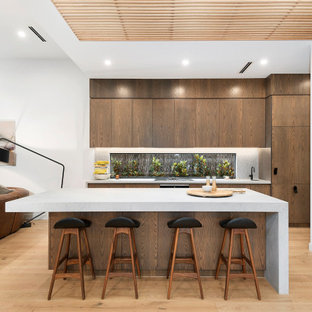 Large contemporary galley open plan kitchen in Melbourne with an undermount sink, flat-panel cabinets, medium wood cabinets, grey splashback, medium hardwood floors, with island, beige floor, grey benchtop and wood.