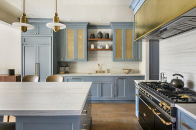 Inspiration for a transitional l-shaped medium tone wood floor and brown floor kitchen remodel in Boston with an undermount sink, shaker cabinets, blue cabinets, white backsplash, black appliances, an island, white countertops, quartzite countertops and granite backsplash
