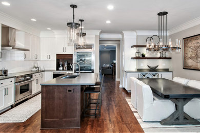 Inspiration for a mid-sized industrial l-shaped dark wood floor and brown floor open concept kitchen remodel in Chicago with an undermount sink, shaker cabinets, white cabinets, quartz countertops, white backsplash, ceramic backsplash, stainless steel appliances, an island and gray countertops