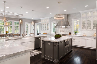 Example of a huge transitional l-shaped dark wood floor and brown floor eat-in kitchen design in Chicago with recessed-panel cabinets, white cabinets, granite countertops, white backsplash, two islands, a farmhouse sink, subway tile backsplash and stainless steel appliances