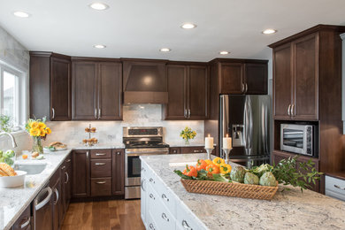 Inspiration for a large transitional galley medium tone wood floor eat-in kitchen remodel in St Louis with an undermount sink, shaker cabinets, dark wood cabinets, granite countertops, white backsplash, stone tile backsplash, stainless steel appliances and an island