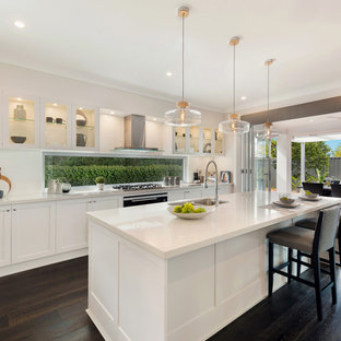 This is an example of a mid-sized contemporary galley eat-in kitchen in Sydney with shaker cabinets, white cabinets, quartz benchtops, white splashback, dark hardwood floors, with island, brown floor, white benchtop and an undermount sink.