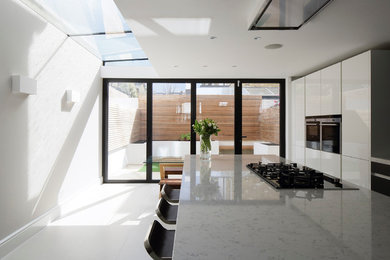 Idéer för att renovera ett stort funkis linjärt kök med öppen planlösning, med en integrerad diskho, släta luckor, vita skåp, granitbänkskiva, stänkskydd i sten, integrerade vitvaror, klinkergolv i keramik, en halv köksö och vitt golv