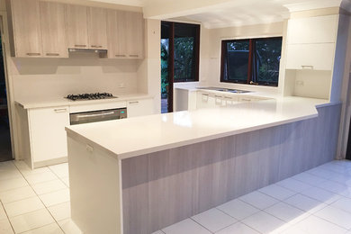 シドニーにある北欧スタイルのおしゃれなキッチン (ダブルシンク、クオーツストーンカウンター、白いキッチンパネル、シルバーの調理設備、セラミックタイルの床、白い床) の写真