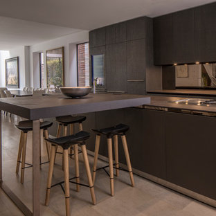 This is an example of a medium sized contemporary single-wall open plan kitchen in London with flat-panel cabinets, brown cabinets, metallic splashback, mirror splashback, stainless steel appliances, an island and grey floors.
