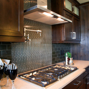 Design ideas for a transitional l-shaped open plan kitchen in Boise with an undermount sink, shaker cabinets, dark wood cabinets, grey splashback, glass tile splashback, stainless steel appliances, medium hardwood floors, with island and recycled glass benchtops.