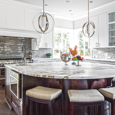 Example of a large transitional u-shaped medium tone wood floor and brown floor kitchen design in Seattle with an undermount sink, shaker cabinets, white cabinets, marble countertops, gray backsplash, glass tile backsplash, paneled appliances, an island and white countertops