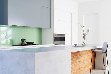 Пример оригинального дизайна: кухня среднего размера в стиле модернизм с обеденным столом, плоскими фасадами, бетонным полом, островом, серыми фасадами, зеленым фартуком, двойной мойкой, фартуком из стекла и техникой из нержавеющей стали