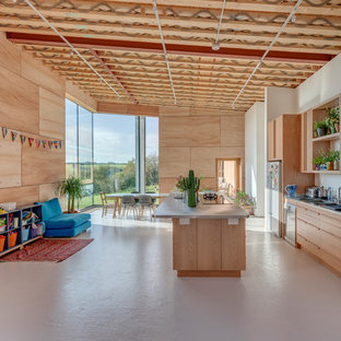 Inspiration for a bohemian galley open plan kitchen in Cornwall with flat-panel cabinets, light wood cabinets, stainless steel appliances, an island, beige floors and grey worktops.