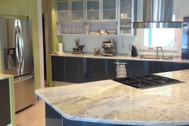 タンパにある広いコンテンポラリースタイルのおしゃれなキッチン (フラットパネル扉のキャビネット、緑のキャビネット、シルバーの調理設備、アンダーカウンターシンク、ベージュの床) の写真