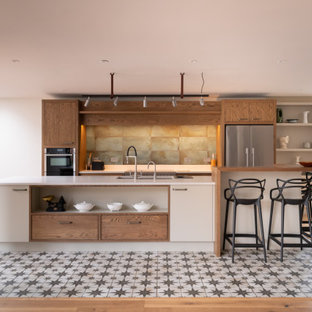 Inspiration for a large contemporary galley kitchen in Kent with a submerged sink, flat-panel cabinets, white cabinets, green splashback, stainless steel appliances, an island, multi-coloured floors and white worktops.