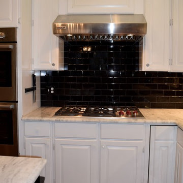 Stainless cooktop and hood with tile backsplash.