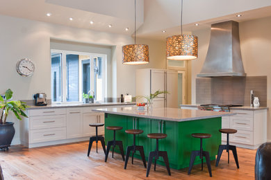Inspiration for a contemporary l-shaped eat-in kitchen remodel in Vancouver with an undermount sink, recessed-panel cabinets, green cabinets, quartz countertops, gray backsplash, glass tile backsplash and paneled appliances