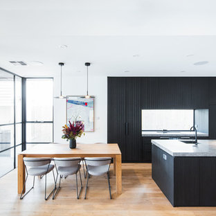 Inspiration for a mid-sized contemporary galley open plan kitchen in Melbourne with black cabinets, quartz benchtops, window splashback, black appliances, with island, grey benchtop, an undermount sink, flat-panel cabinets, medium hardwood floors and brown floor.