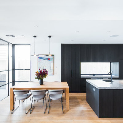 Example of a mid-sized trendy galley medium tone wood floor and brown floor open concept kitchen design in Melbourne with black cabinets, quartz countertops, window backsplash, black appliances, an island, gray countertops, an undermount sink and flat-panel cabinets