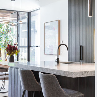 Inspiration for a mid-sized contemporary galley open plan kitchen in Melbourne with black cabinets, quartz benchtops, light hardwood floors, with island, grey benchtop, an undermount sink, flat-panel cabinets and beige floor.