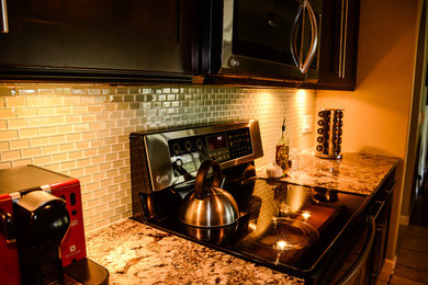 Ejemplo de cocina comedor actual con armarios tipo vitrina, puertas de armario en acero inoxidable, encimera de granito y electrodomésticos de acero inoxidable