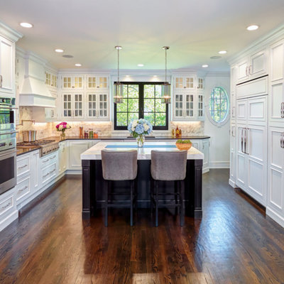 Example of a transitional u-shaped dark wood floor and brown floor kitchen design in Detroit with an undermount sink, recessed-panel cabinets, white cabinets, white backsplash, stainless steel appliances, an island and white countertops