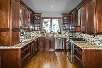 Enclosed kitchen - mid-sized traditional u-shaped light wood floor and brown floor enclosed kitchen idea in New York with an undermount sink, raised-panel cabinets, brown cabinets, granite countertops, multicolored backsplash, marble backsplash, stainless steel appliances and no island