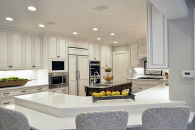 Inspiration for a transitional kitchen remodel in Charlotte with an undermount sink, recessed-panel cabinets, white cabinets, white backsplash, ceramic backsplash and paneled appliances
