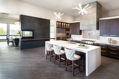 Expansive contemporary l-shaped open plan kitchen in Chicago with a submerged sink, shaker cabinets, dark wood cabinets, engineered stone countertops, metallic splashback, mosaic tiled splashback, stainless steel appliances, dark hardwood flooring, an island and brown floors.