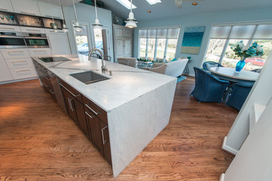 Example of a mid-sized trendy galley medium tone wood floor and brown floor open concept kitchen design in Baltimore with flat-panel cabinets, white cabinets, marble countertops, an island, an undermount sink, white backsplash, mosaic tile backsplash and stainless steel appliances