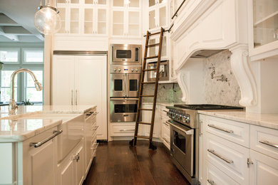 Ejemplo de cocina actual grande con armarios tipo vitrina, electrodomésticos de acero inoxidable, suelo de madera oscura y una isla