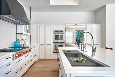 This is an example of a medium sized bohemian u-shaped kitchen in Dallas with a single-bowl sink, shaker cabinets, white cabinets, engineered stone countertops, white splashback, porcelain splashback, stainless steel appliances, light hardwood flooring, an island, beige floors and white worktops.