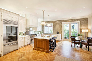 Example of a mid-sized classic l-shaped light wood floor eat-in kitchen design in San Francisco with an undermount sink, recessed-panel cabinets, beige cabinets, beige backsplash, stainless steel appliances and an island
