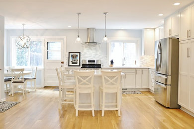 Example of a mid-sized transitional l-shaped light wood floor and beige floor open concept kitchen design in Chicago with an undermount sink, shaker cabinets, white cabinets, quartz countertops, multicolored backsplash, mosaic tile backsplash, stainless steel appliances and an island