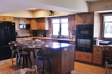 Mid-sized l-shaped eat-in kitchen photo in Other with flat-panel cabinets, medium tone wood cabinets, quartz countertops, beige backsplash, black appliances and an island