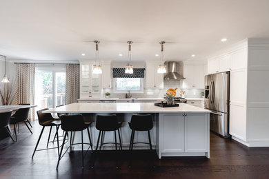 Large transitional l-shaped brown floor open concept kitchen photo in Montreal with a single-bowl sink, shaker cabinets, white cabinets, quartzite countertops, gray backsplash, subway tile backsplash, stainless steel appliances, an island and white countertops