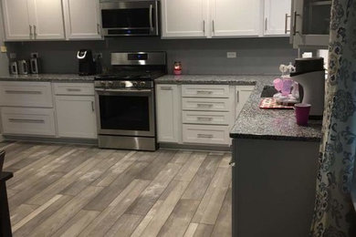 Large transitional u-shaped brown floor and medium tone wood floor enclosed kitchen photo in Chicago with an undermount sink, shaker cabinets, white cabinets, granite countertops, stainless steel appliances and no island