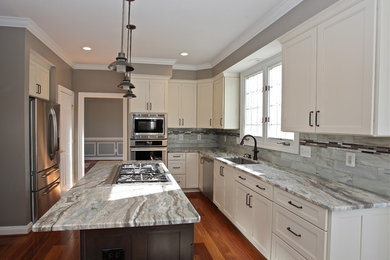 Inspiration for a mid-sized transitional l-shaped medium tone wood floor eat-in kitchen remodel in DC Metro with an undermount sink, shaker cabinets, white cabinets, granite countertops, glass tile backsplash, stainless steel appliances, an island and multicolored backsplash