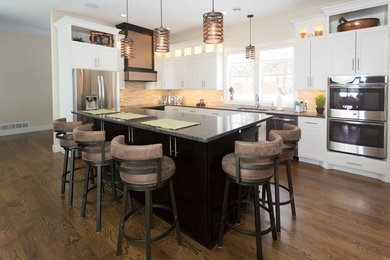 Inspiration for a mid-sized transitional l-shaped dark wood floor kitchen remodel in San Diego with an undermount sink, recessed-panel cabinets, white cabinets, quartz countertops, beige backsplash, porcelain backsplash, stainless steel appliances and an island