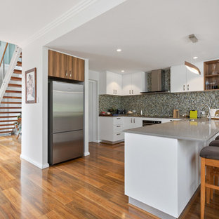 Inspiration for a transitional u-shaped kitchen in Perth with an undermount sink, flat-panel cabinets, white cabinets, grey splashback, mosaic tile splashback, stainless steel appliances, medium hardwood floors, brown floor and grey benchtop.