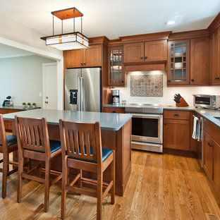 Mid-sized craftsman open concept kitchen appliance - Example of a mid-sized arts and crafts l-shaped medium tone wood floor and brown floor open concept kitchen design in Nashville with an undermount sink, shaker cabinets, medium tone wood cabinets, quartz countertops, white backsplash, ceramic backsplash, stainless steel appliances and an island