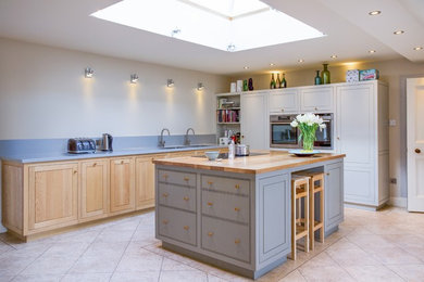 This is an example of a large contemporary l-shaped kitchen/diner in Edinburgh with a double-bowl sink, recessed-panel cabinets, light wood cabinets, wood worktops, stainless steel appliances and an island.
