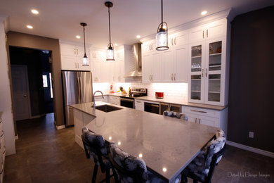 Example of a mid-sized transitional l-shaped porcelain tile and gray floor eat-in kitchen design in Ottawa with an undermount sink, shaker cabinets, white cabinets, quartz countertops, white backsplash, ceramic backsplash, stainless steel appliances, an island and gray countertops
