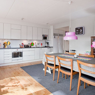 Mid-sized danish single-wall medium tone wood floor eat-in kitchen photo in Stockholm with flat-panel cabinets, white cabinets, white backsplash, white appliances, a single-bowl sink, subway tile backsplash and no island