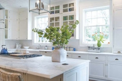 Example of a large classic l-shaped dark wood floor eat-in kitchen design in Other with a farmhouse sink, recessed-panel cabinets, white cabinets, marble countertops, white backsplash, cement tile backsplash, paneled appliances and an island