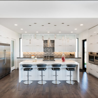 Kitchen - large contemporary l-shaped brown floor kitchen idea in Salt Lake City with an undermount sink, flat-panel cabinets, white cabinets, gray backsplash, matchstick tile backsplash, stainless steel appliances, an island and gray countertops