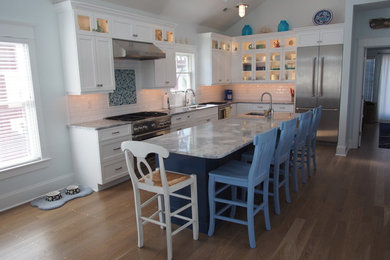 Eat-in kitchen - mid-sized coastal l-shaped light wood floor eat-in kitchen idea in Philadelphia with an undermount sink, shaker cabinets, white cabinets, granite countertops, white backsplash, subway tile backsplash, stainless steel appliances and an island