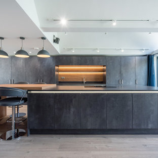 Design ideas for an expansive modern kitchen in London with flat-panel cabinets, grey cabinets, light hardwood flooring, an island, beige floors and grey worktops.