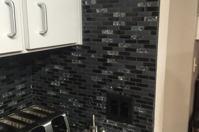 Eat-in kitchen - modern eat-in kitchen idea in Tampa with granite countertops, black backsplash and mosaic tile backsplash