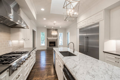 Large elegant galley dark wood floor and brown floor enclosed kitchen photo in Dallas with an undermount sink, raised-panel cabinets, white cabinets, gray backsplash, porcelain backsplash, stainless steel appliances, an island and quartz countertops