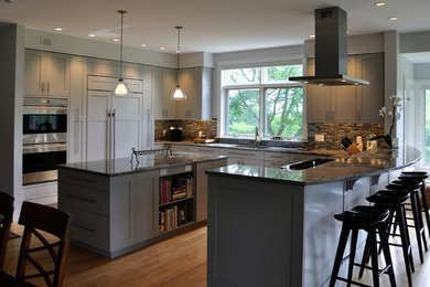 Diseño de cocina clásica con armarios con paneles empotrados, puertas de armario grises, encimera de granito, electrodomésticos de acero inoxidable y una isla